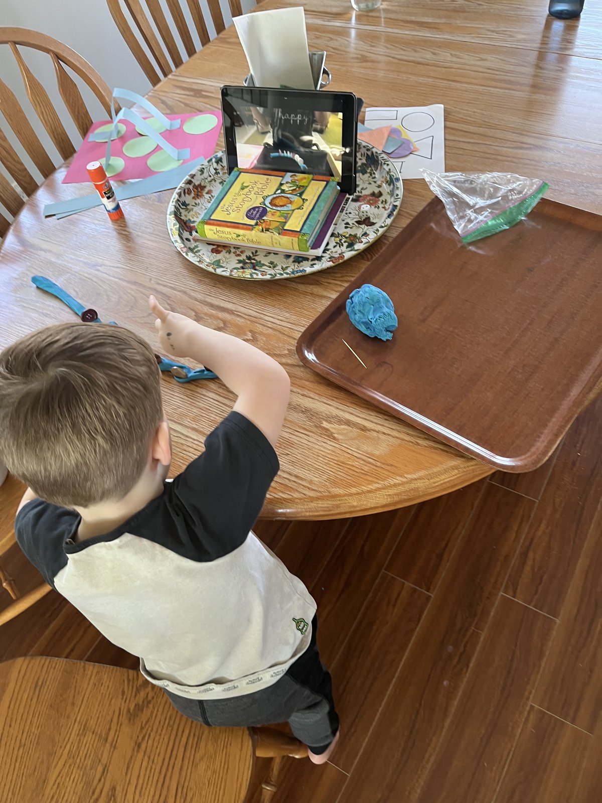 Child participating in Busy Bees class on a tablet with supplies laid out