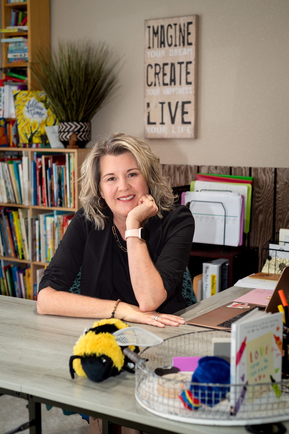 Joanne McMahon, founder of Busy Bees Early Childhood Learning, at her desk surrounded by books and learning materials